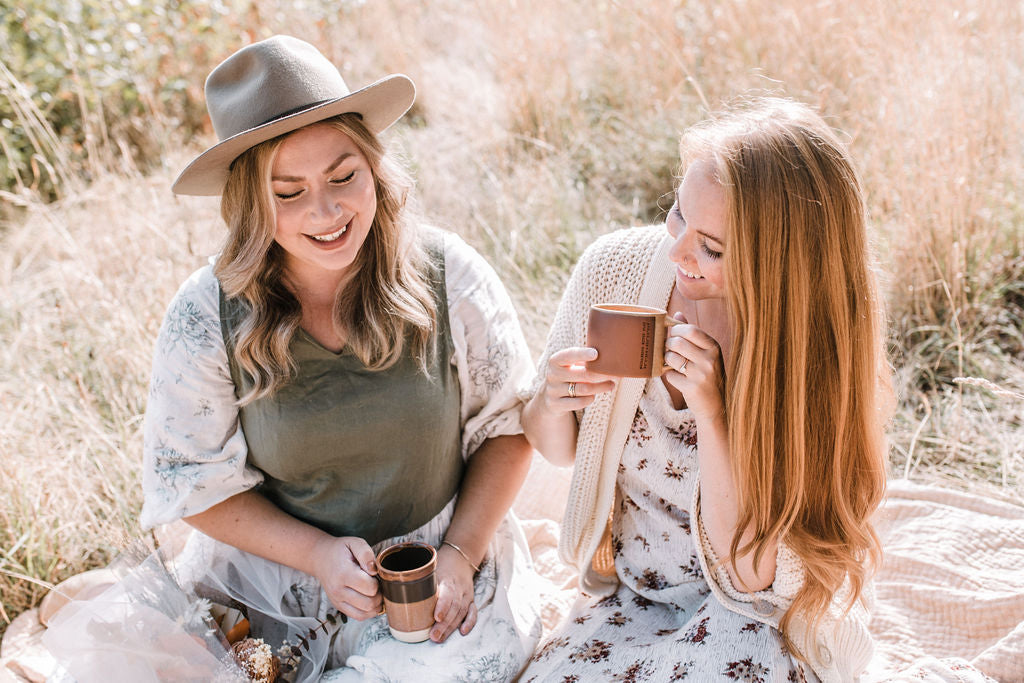 Two women enjoying a picnic in a sunny meadow.
