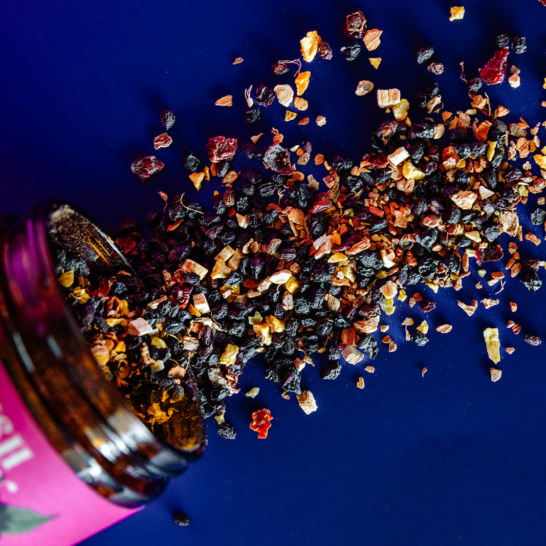 Spices spilling out of a pink bottle on a blue background