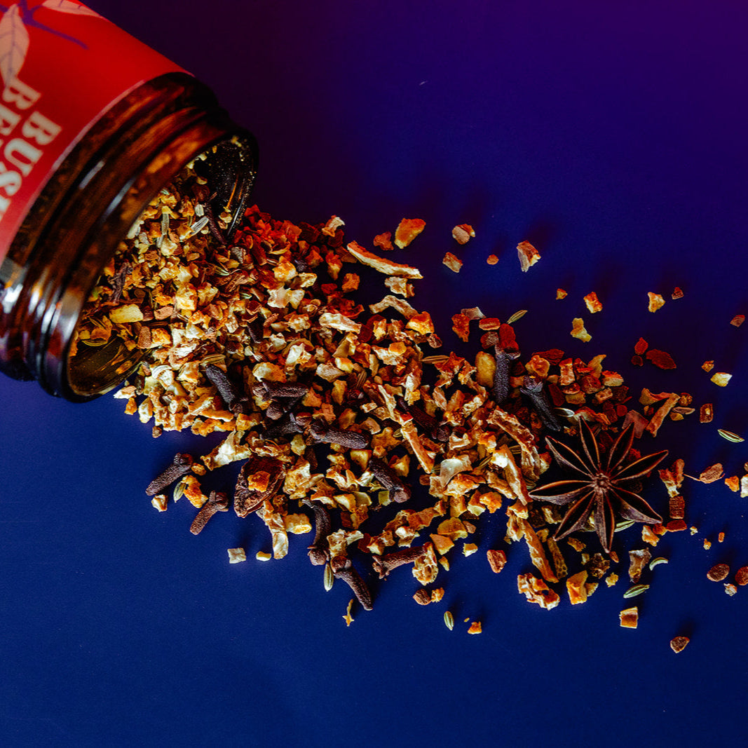 Mulling Spices spilling out of a red and white container on a blue background