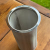 Metal mesh filter on a wooden surface with grass in the background