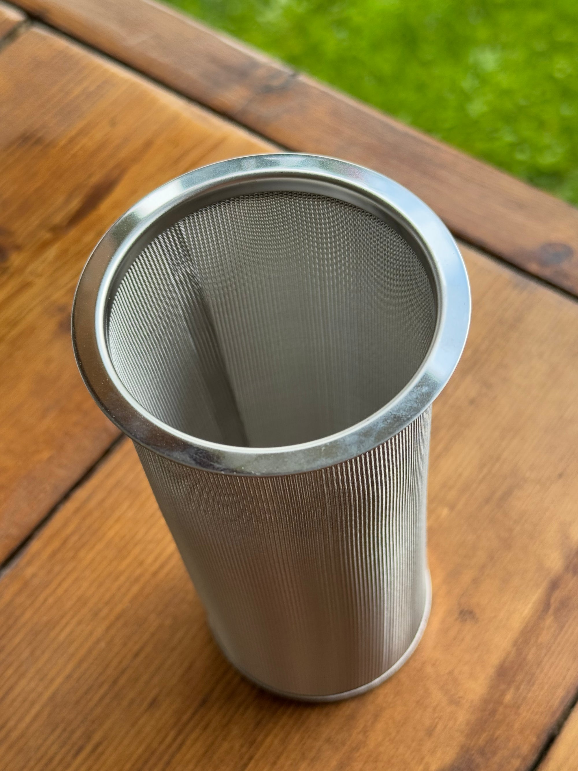 Metal mesh filter on a wooden surface with grass in the background