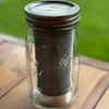 Glass jar with a metal lid on a wooden surface with a green blurred background