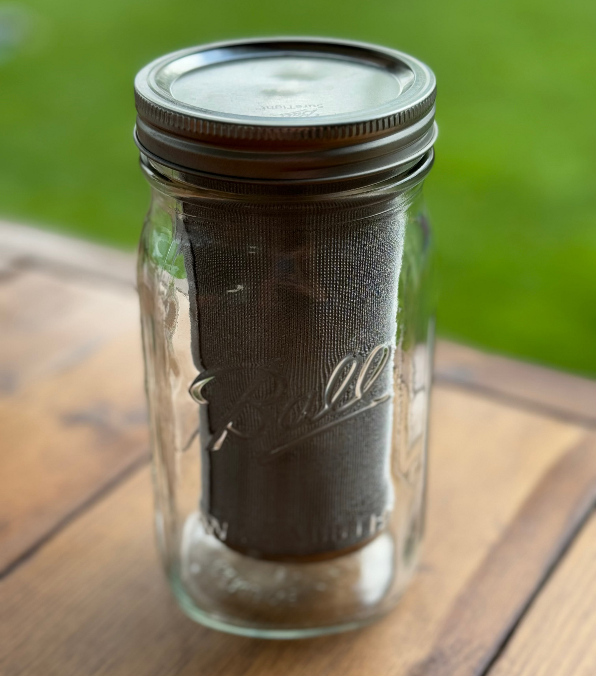 Glass jar with a metal lid on a wooden surface with a green blurred background