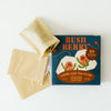 A box of Bush Berry loose leaf tea filter alongside two beige reusable paper tea bags on a clean white background.