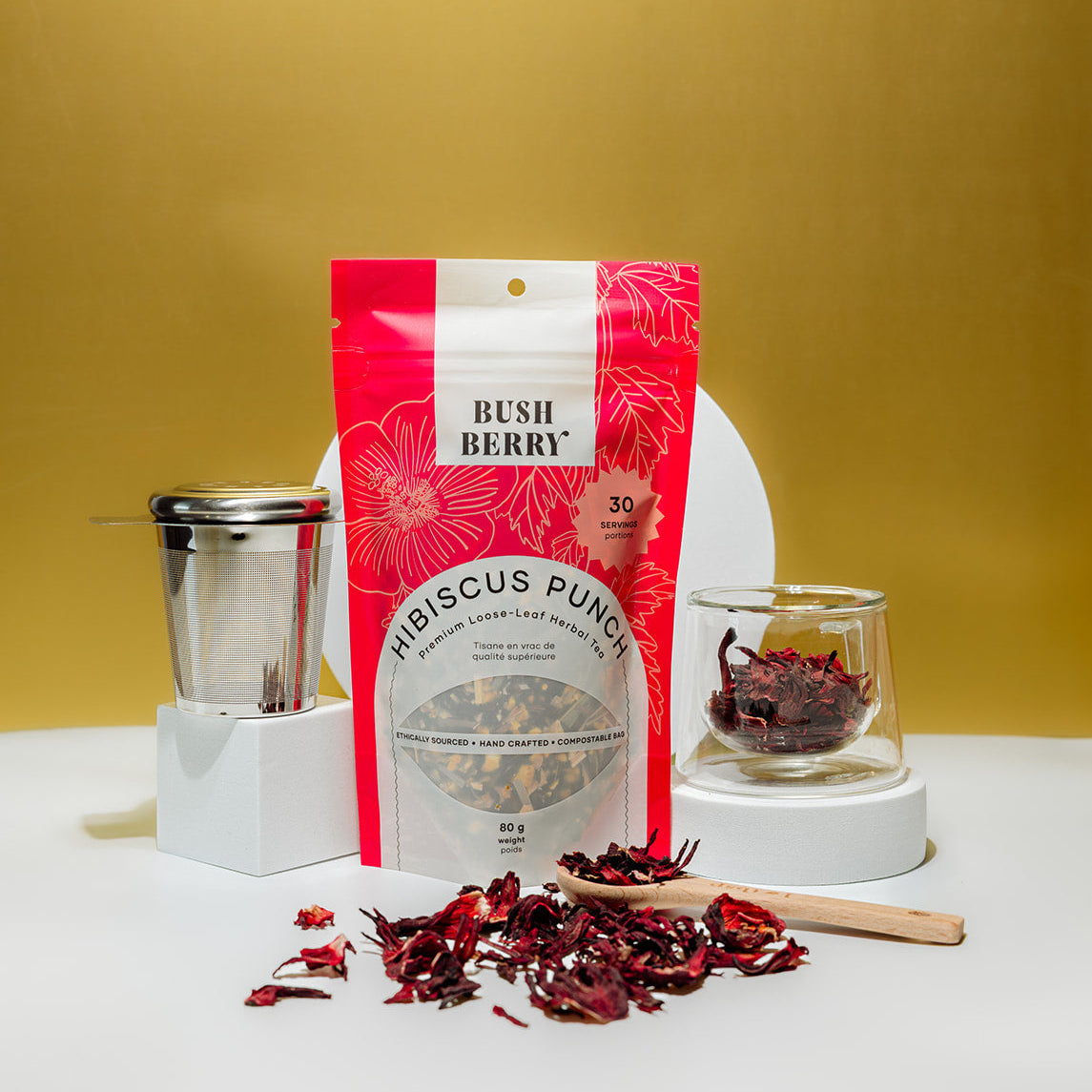 Hibiscus berry tea package with loose tea on a white surface against a yellow background