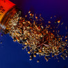 Spices spilling out of a labeled container on a blue background