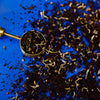 Tea leaves in a scoop on a blue background