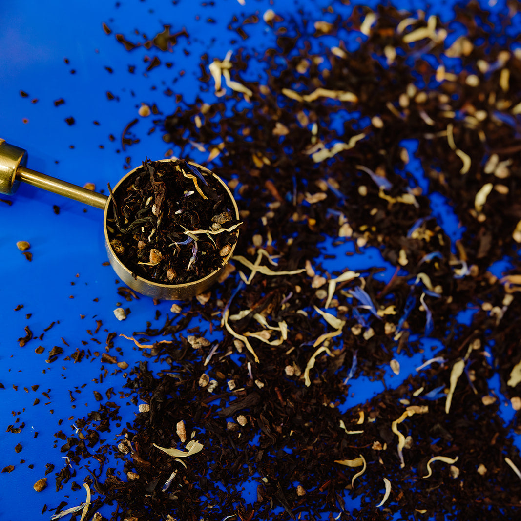 Tea leaves in a scoop on a blue background