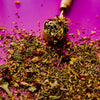 Tea leaves with a wooden scoop on a purple background