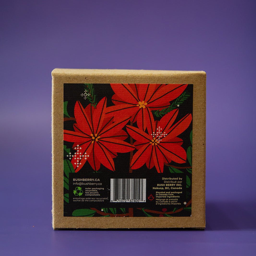A square kraft paper box with a decorative front label featuring red poinsettia flowers on a black background, photographed against a solid purple backdrop.