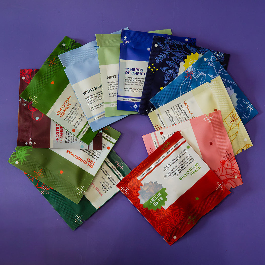 A circular arrangement of multiple small colorful product pouches on a solid purple background. The pouches feature different holiday-themed designs and labels in red, green, blue, pink, yellow, and white.