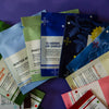 A fan arrangement of assorted tea sachets in various colors and designs, including green, blue, mint green, navy, and cream, with visible text labels such as 'Winter White', 'Mint Tea', '12 Herbs of Christmas', 'Raspberry Chamomile', and 'Vanilla Cinnamon'.