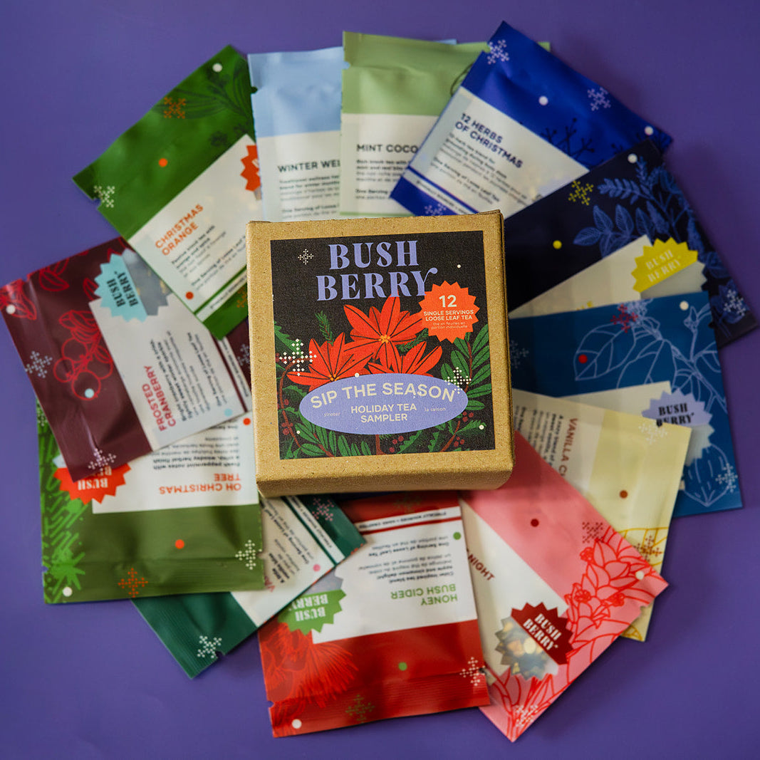A circular arrangement of colorful tea bags and a central wooden box labeled 'BUSH BERRY SIP THE SEASON' on a solid purple background.
